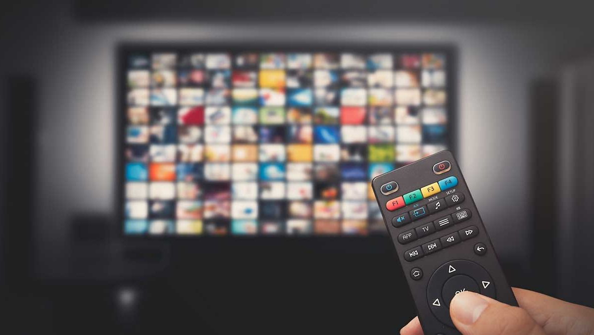 A hand is on a remote for the TV in the background, with many boxes indicating the different streaming options.